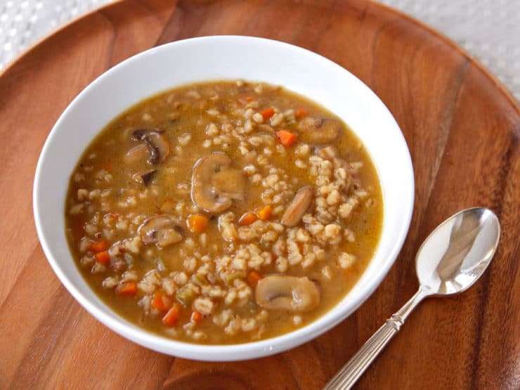 Image of a Mushroom Barley Soup served on a white bowl with spoon on side