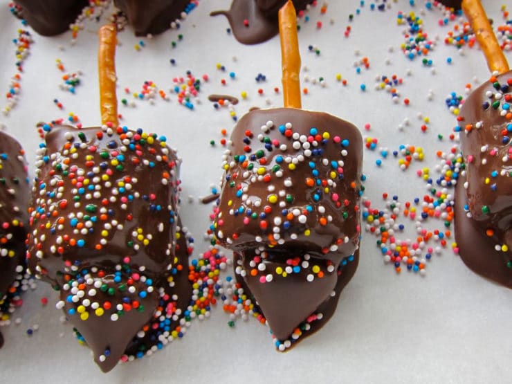 Candy dreidels in melted chocolate coated in sprinkles.