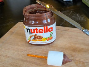 Jar of Nutella with candy dreidel in front and knife for spreading.