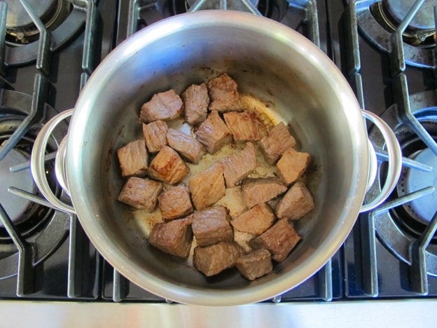 Browning chunks of beef on the stove.