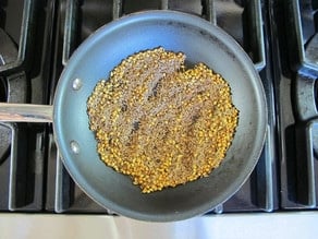 Toasting spices in skillet on stovetop.