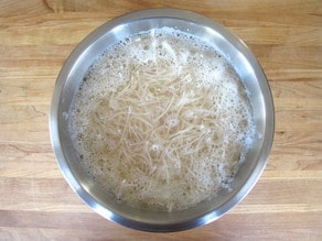Shredded potatoes in a bowl of water.