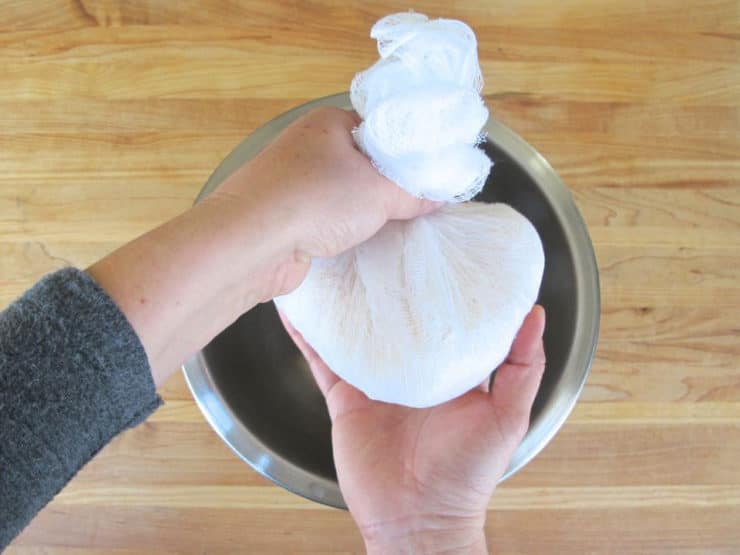 Squeezing moisture from potatoes in cheesecloth.