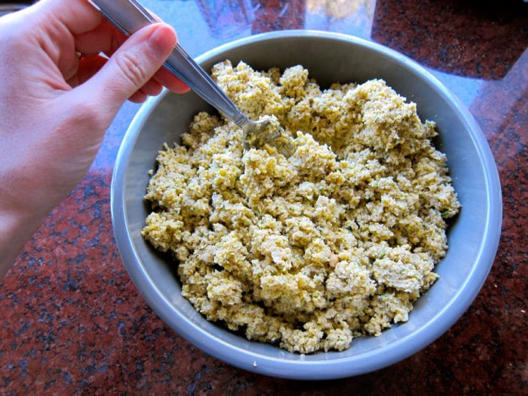 Fork stirring falafel mixture in a bowl.