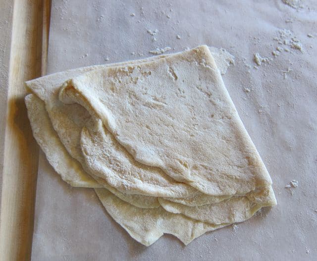 Rolled dough folded in quarters on parchment.