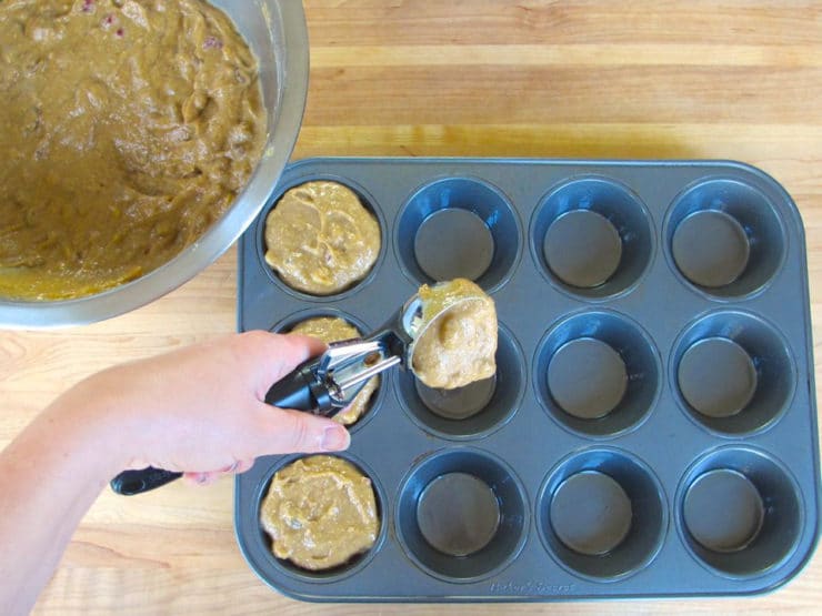 Scooping muffin batter into prepared tin.
