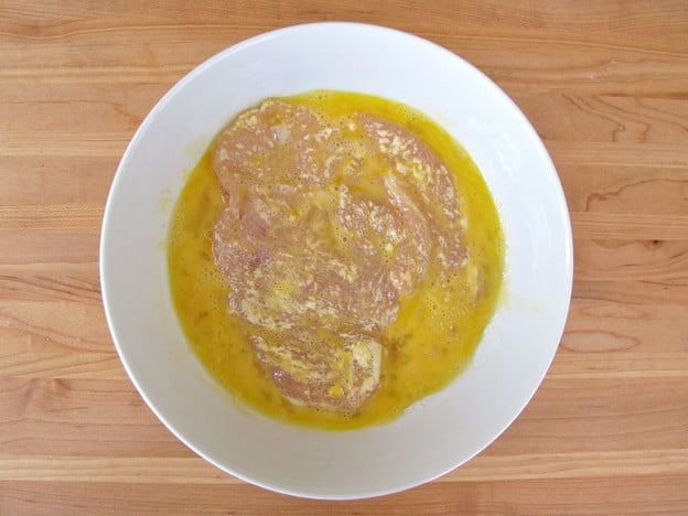 Dipping chicken breast in egg.