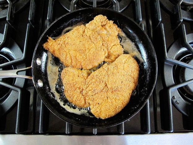 Frying chicken schnitzel in a skillet.