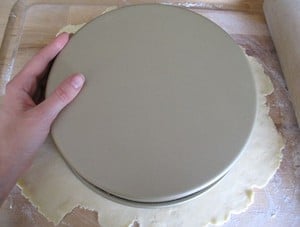 Tracing a cake pan onto rolled dough for a circle.