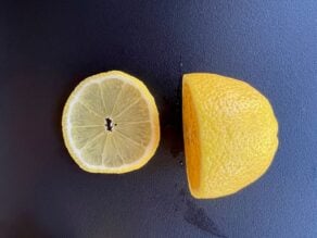 Sliced lemon round beside a half lemon.