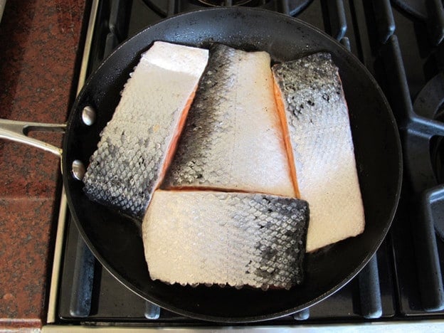 Searing salmon fillets in a skillet.