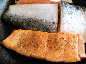 Searing salmon fillets in a skillet.