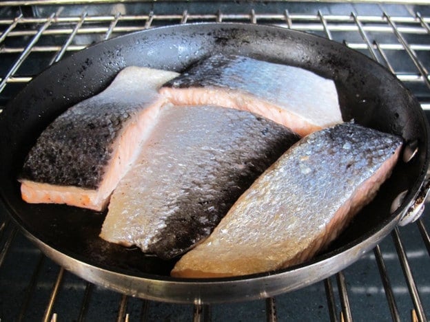 Searing salmon fillets in a skillet.