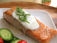 Seared salmon with creamy dill sauce and cucumbers on a plate