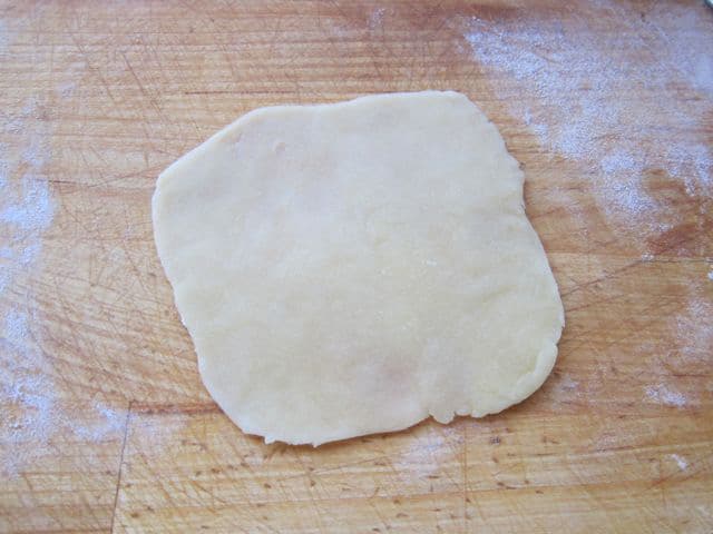 Dough rolled in a rough circle.