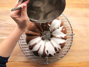 Pouring lemon frosting over bundt cake.