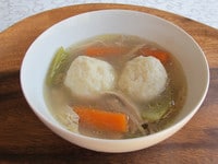 A bowl of Chicken Soup with Matzah Balls, turnip, and carrots