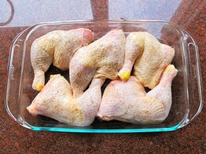 Chicken quarters in a baking dish.