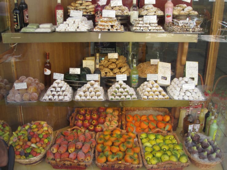 Cookies and treats, many made with almond paste, in stacks in a colorful window display - Taormina, Italy.