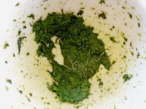 Basil pulverized in pestle - close up - with basil juices collecting.