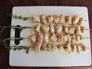 Marinated chicken cubes on rosemary stems.
