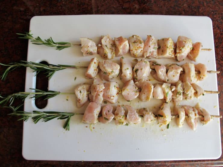 Marinated chicken cubes on rosemary stems.