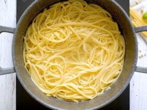 A large pot of cooked pasta in water on a small induction cooktop.
