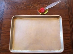 Brushing a baking sheet with olive oil.