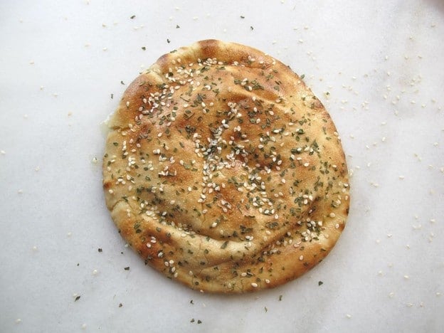Sesame seeds sprinkled over oiled pita rounds.