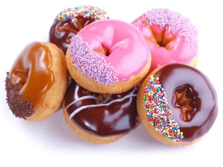 Pilot of colorful frosted doughnuts in various flavors on a white background.