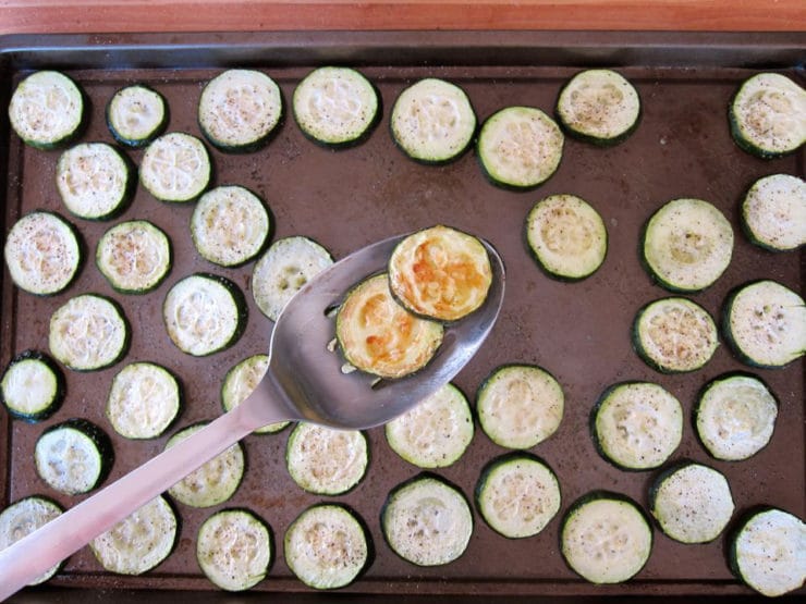 Flipping over sliced potatoes on a baking sheet.