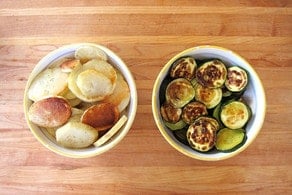 Roasted potatoes and zucchini in separate bowls.