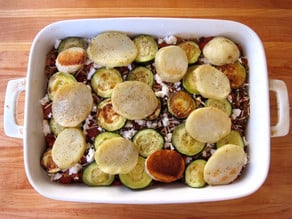 Roasted potatoes and zucchini layered in a baking dish.
