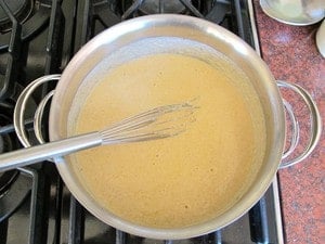 Whisking parmesan cheese into bechamel sauce.