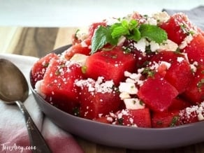 Close up of watermelon feta salad with mint, spoon and napkin beside it.