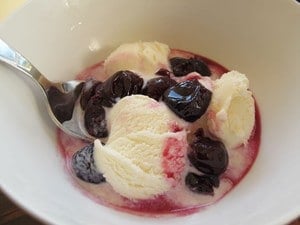 Preserved cherries in a bowl of vanilla ice cream.