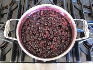Cherries in reduced sauce in a saucepan.