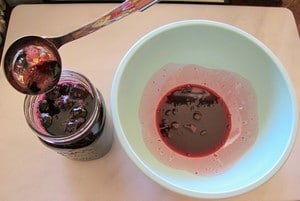Funneling cherries into a canning jar.
