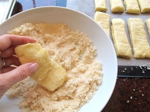 Dipping twisted dough in vanilla sugar.