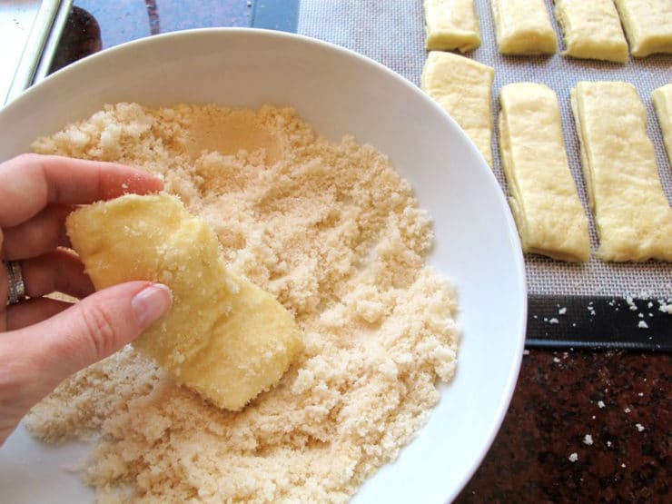 Dipping twisted dough in vanilla sugar.