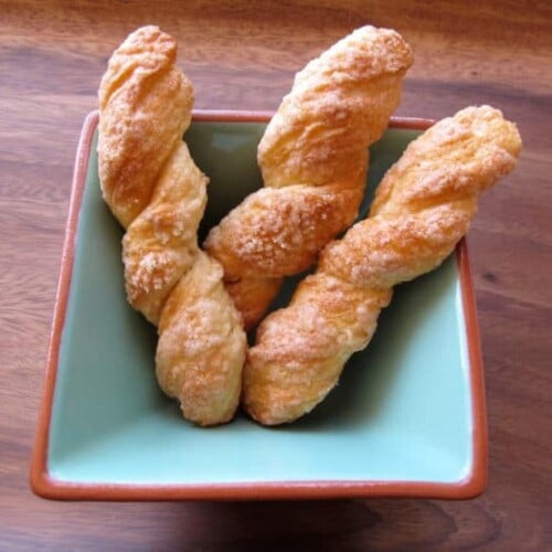 Image of Sour Cream Twists in a rectangular bowl on top of a wood table.