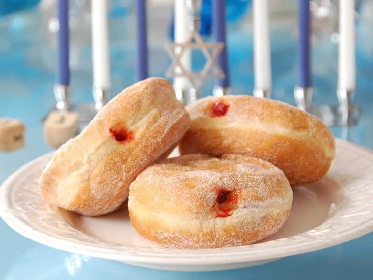 Sufganiyot - Jewish Jelly Filled Doughnuts with Hanukkiah - Menorah and Jewish Star of David in background