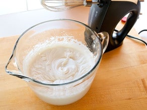 Whipping cream in a glass measuring cup.