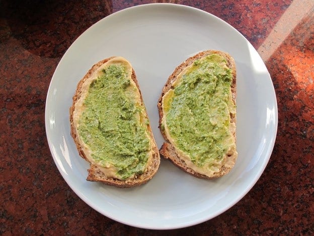 Hummus and pesto spread on sliced bread.