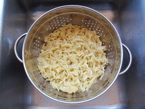 Cooked noodles draining in a colander.