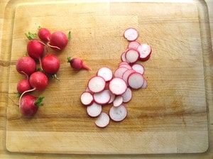 Radishes sliced into rounds on a cutting board.
