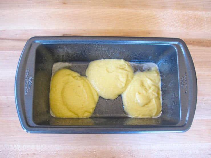 Small rectangular cake pan with three dollops of yellow batter, staggered.