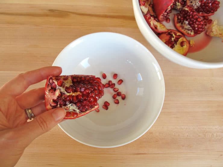 Loosen seeds from each section of pomegranate into a bowl.