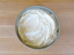 Thickened strained yogurt in bowl on cutting board.