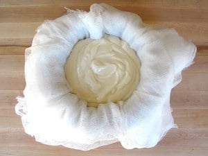 Yogurt in cheesecloth-lined mesh colander.